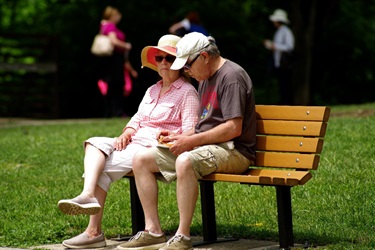 Older couple enjoying a snack on a park bench