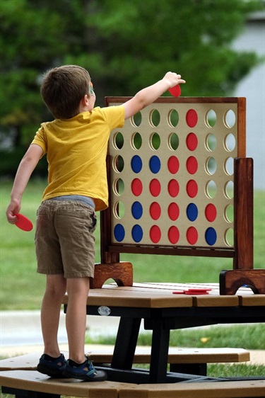 Young boy places red checker in connect four game