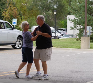 A couple enjoying an afternoon dance in the parkling lot at the marketplace