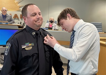 A closeup of Capt. Waters getting pinned with a new badge by his teenage son.