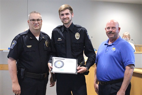 Officer Nick Moeller receiving a certificate and pin from Merriam Police Chief Darren McLaughlin with Mayor Ken Sissom on the right side.