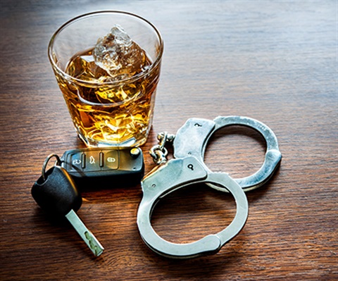 Picture of a whiskey drink sitting next to a pair of keys and handcuffs