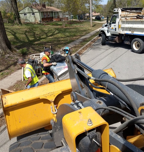 Picture from high angle of two men putting boxes of trash on a construction truck.