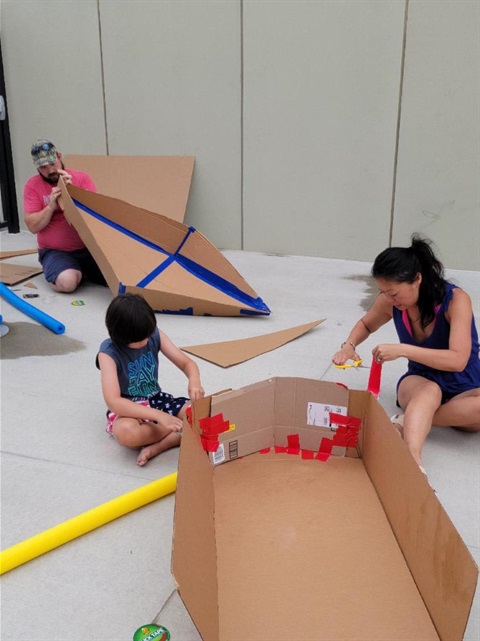 Families building cardboard boats