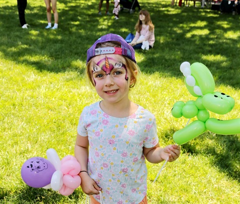 Child with face painted and balloon art