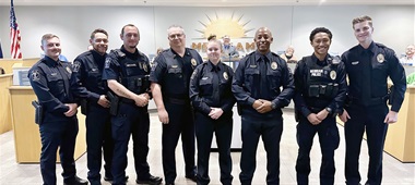 Seven new police officers flank Police Chief Darren Mclaughlin at a Merriam City Council meeting.