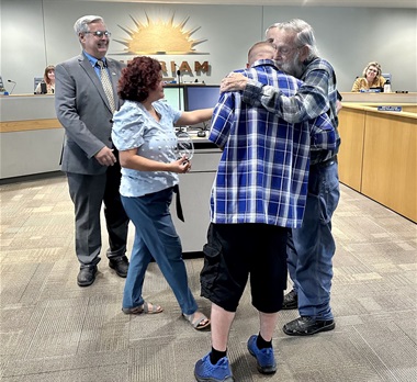 Jerrod Young hugs Ralph Cochran at a Merriam City Council meeting.