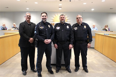 Two Merriam police officers in full dress are flanked by Mayor Bob Pape and Police Chief Darren McLaughlin inside the Merriam City Council chambers.