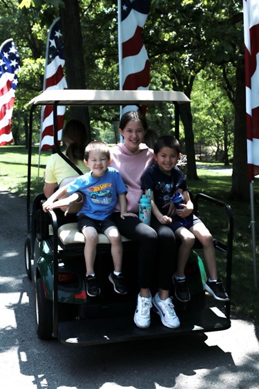 a young girl and two young boys riding on the back of a golf cart