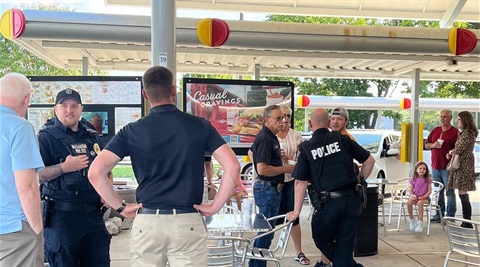 Merriam police officers are talking with community members outside of a Sonic restaurant.